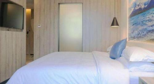 a bedroom with a white bed and a television at hailihotel in Dongguan