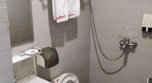 a small bathroom with a toilet and a shower at Shell Hotel Shanghai Baoshan Meilanhu Luosheng Road in Shanghai