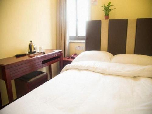 a bedroom with a bed and a wooden desk at Shell Hotel Shanghai Baoshan Meilanhu Luosheng Road in Shanghai
