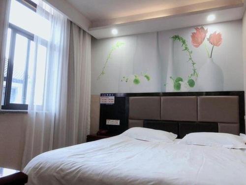 a bedroom with a bed with flowers on the wall at Shell Hotel Shanghai Baoshan Meilanhu Luosheng Road in Shanghai