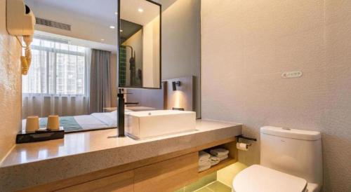 une salle de bain avec un lavabo, des toilettes et un miroir dans l'établissement GreenTree Inn Wuxi Quanshan Center, à Wuxi