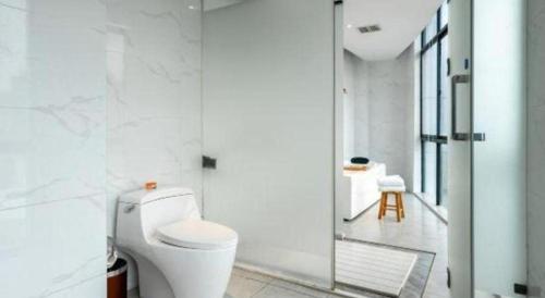 a white bathroom with a toilet and a shower at Kyriad Marvelous Hotel Xiangyin Bus Station in Xiangyin