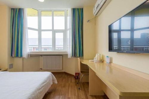 a bedroom with a bed and a desk and windows at 7Days Inn Tianjin Fifth Avenue Youyi Road Branch in Tianjin
