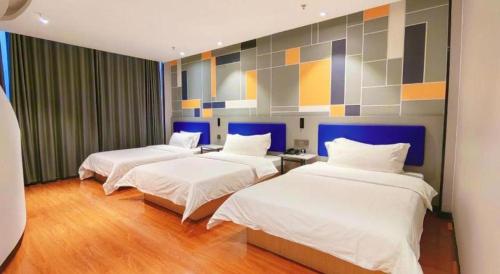 a room with three beds and a painting on the wall at 7 Days Inn Yining Xintiandi in Kipekyüzi