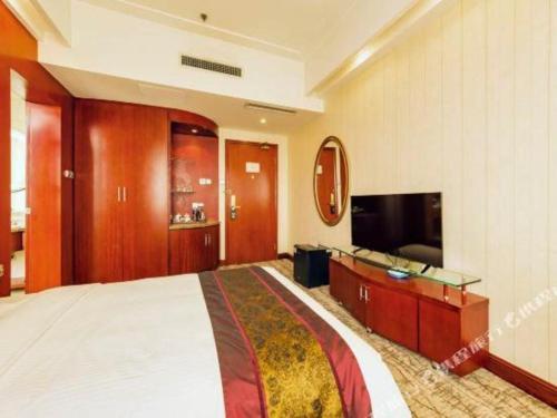 a hotel room with a large bed and a flat screen tv at Junyu Grand Hotel Qinhuangdao in Qinhuangdao