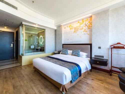 a bedroom with a large bed and a large window at Junyu Grand Hotel Qinhuangdao in Qinhuangdao