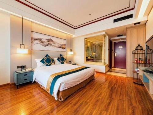a bedroom with a large bed and a desk at Junyu Grand Hotel Qinhuangdao in Qinhuangdao
