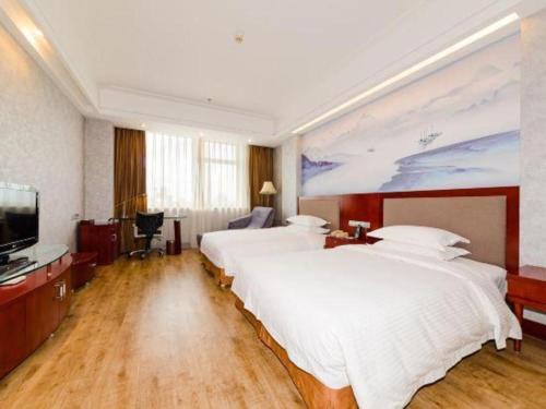 a large bedroom with two beds and a television at Junyu Grand Hotel Qinhuangdao in Qinhuangdao
