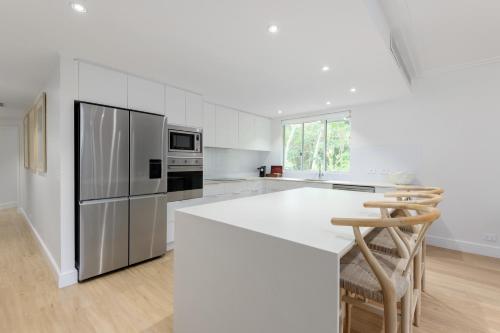 a white kitchen with a white counter and a refrigerator at Mandalay Luxury Beachfront Apartments in Port Douglas