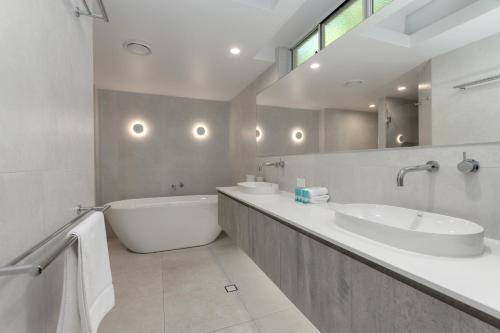 a bathroom with two sinks and a bath tub at Mandalay Luxury Beachfront Apartments in Port Douglas