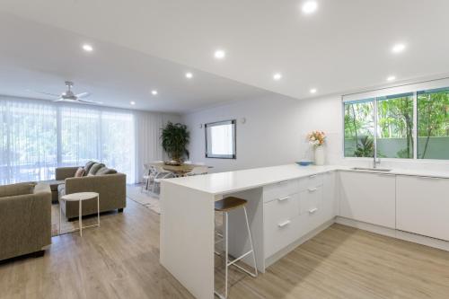 a kitchen with white cabinets and a living room at Mandalay Luxury Beachfront Apartments in Port Douglas
