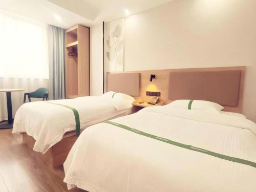 a hotel room with two beds and a table at GreenTree Inn Gaoyou Government in Yangzhou