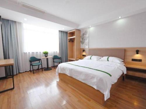 a bedroom with a large bed and a table and chairs at GreenTree Inn Gaoyou Government in Yangzhou