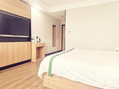 a bedroom with a large bed and a flat screen tv at GreenTree Inn Gaoyou Government in Yangzhou