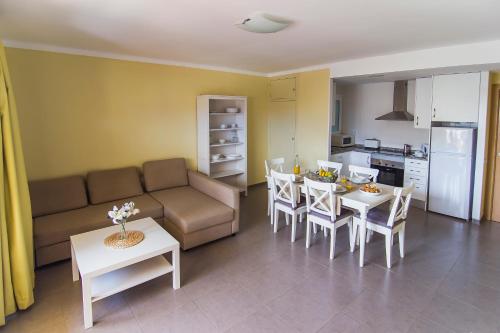 ein Wohnzimmer mit einem Sofa, einem Tisch und Stühlen in der Unterkunft RVHotels Apartamentos El Quijote in L'Estartit