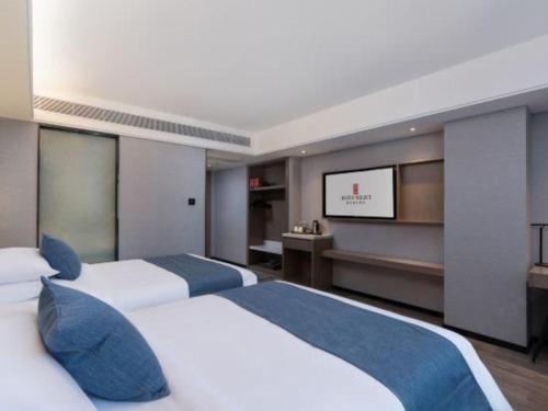 two beds in a hotel room with a flat screen tv at Nanning Prince Hotel in Nanning