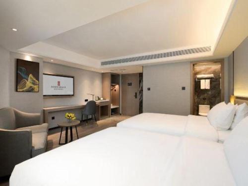 a hotel room with a large white bed and a desk at Nanning Prince Hotel in Nanning