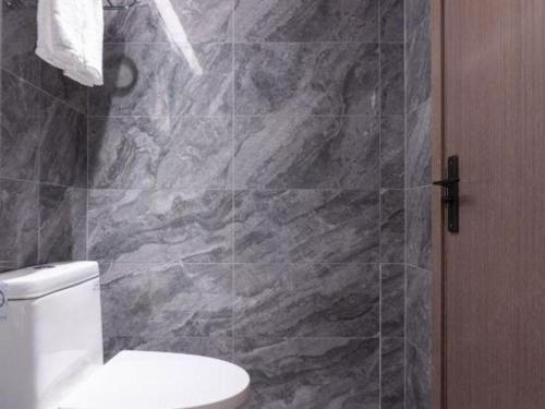 a bathroom with a toilet and a stone wall at Nanning Prince Hotel in Nanning