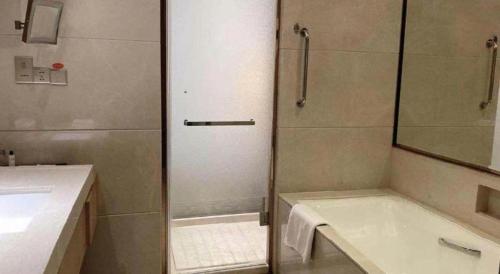 a bathroom with a shower and a tub and a sink at Dusit D2 Binhu Changzhou Hotel in Changzhou