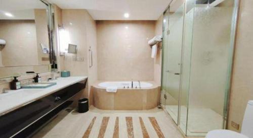a bathroom with a tub and a glass shower at Dusit D2 Binhu Changzhou Hotel in Changzhou