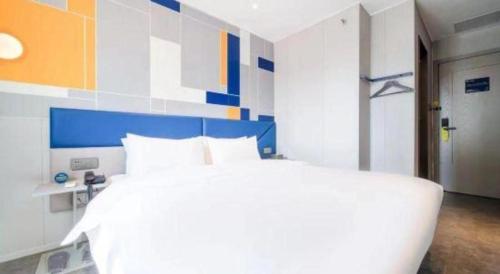 a bedroom with a white bed and a blue and white wall at 7 Days Inn Chengdu Sichuan University South Railway Station in Chengdu