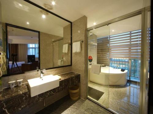 a bathroom with a sink and a tub and a mirror at GreenTree Inn Fujian Fuzhou Software Park River View Business Hotel in Fuzhou