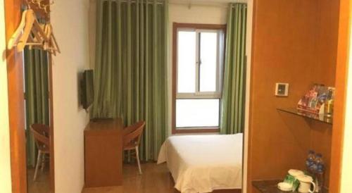 a bedroom with a bed and a window with green curtains at GreenTree Inn Hefei Huangshan Road Daxidi 1912 Express Hotel in Hefei