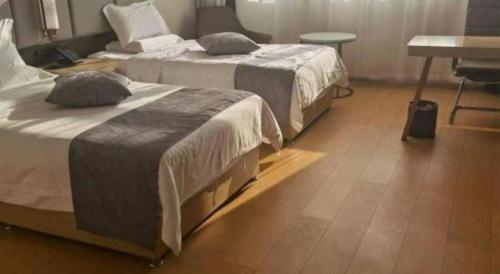 two beds in a room with a table and a desk at GreenTree Inn Taiyuan PinGYAng Road Business Hotel in Taiyuan