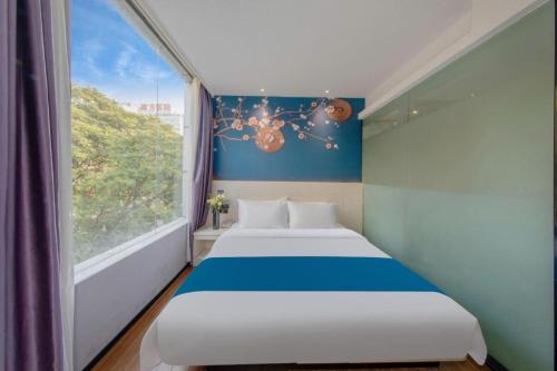 a bed in a room with a large window at Wenxing Hotel Guangzhou Nanfang Hospital Branch in Guangzhou
