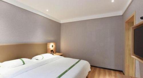 a bedroom with a large white bed and a flat screen tv at GreenTree Inn Hefei Chenghuangmiao San Xiao Kou Subway Station Hotel in Hefei