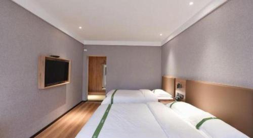 a bedroom with a large bed and a flat screen tv at GreenTree Inn Hefei Chenghuangmiao San Xiao Kou Subway Station Hotel in Hefei