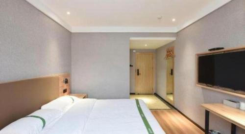 a bedroom with a large bed and a flat screen tv at GreenTree Inn Hefei Chenghuangmiao San Xiao Kou Subway Station Hotel in Hefei