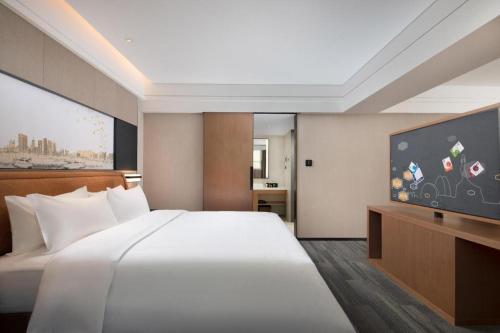 a bedroom with a large bed and a flat screen tv at Hampton by Hilton Zhuhai Doumen in Zhuhai
