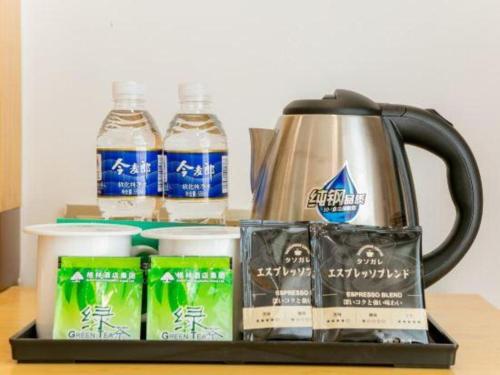 a tray with a tea kettle and drinks on a table at GreenTree Inn Qufu High Speed Railway Station in Jining