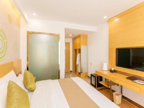 a hotel room with a bed and a flat screen tv at GreenTree Inn Qufu High Speed Railway Station in Jining