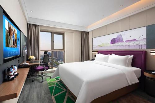 a hotel room with a large white bed and a desk at Hampton by Hilton Zhuhai Doumen in Zhuhai