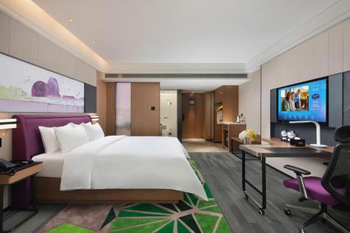 a bedroom with a large bed and a desk and a computer at Hampton by Hilton Zhuhai Doumen in Zhuhai