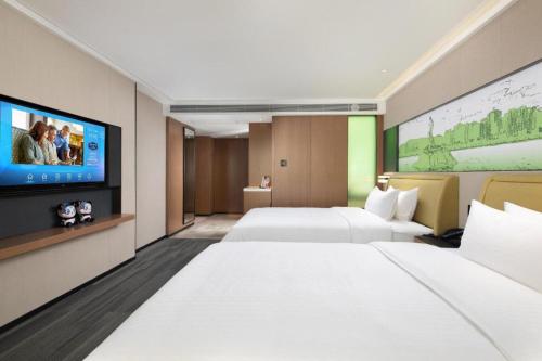 a hotel room with two beds and a flat screen tv at Hampton by Hilton Zhuhai Doumen in Zhuhai