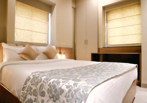 a bedroom with a large bed and two windows at The Falcon Inn in Mumbai