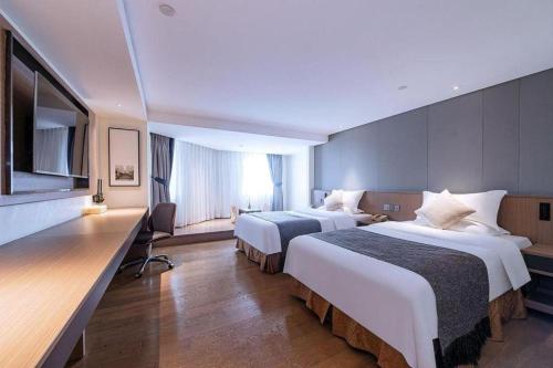 a hotel room with two beds and a television at Zhongshan Louis Hotel in Zhongshan