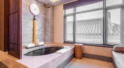 a large bathroom with a tub in front of a large window at Xian Huaqingyutang Hotel in Xi'an