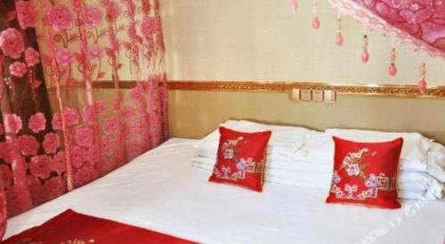 a bedroom with a bed with red and white pillows at Pingyao Yufengheng Hotel in Pingyao
