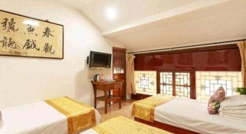 a hotel room with two beds and a desk at Pingyao Yufengheng Hotel in Pingyao