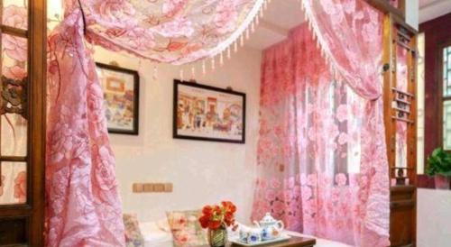 a room with pink curtains and a room with a bed at Pingyao Yufengheng Hotel in Pingyao