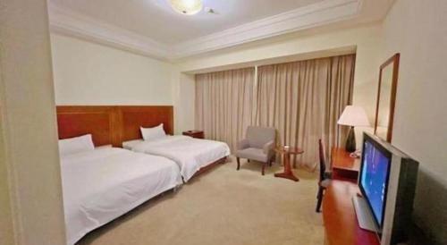a hotel room with two beds and a flat screen tv at Changshu Jinling Tianming Grand Hotel in Suzhou