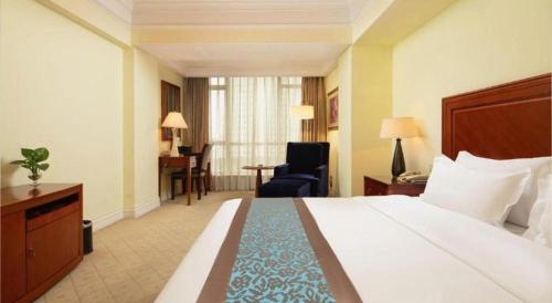 a hotel room with a large bed and a desk at Changshu Jinling Tianming Grand Hotel in Suzhou