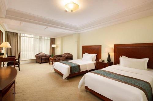 a hotel room with two beds and a desk at Changshu Jinling Tianming Grand Hotel in Suzhou