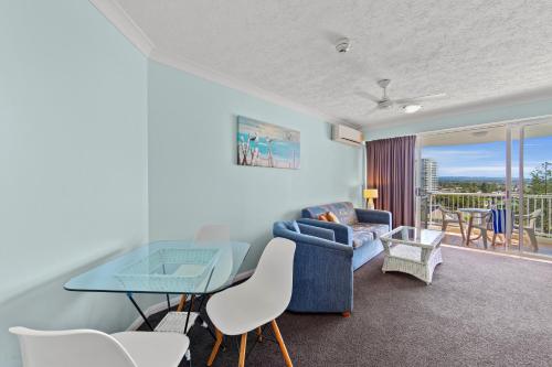 a living room with a blue couch and a glass table at Surf Parade Resort in Gold Coast