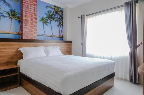 a bedroom with a bed and a window with palm trees at Noura Guest House Syariah in Malang