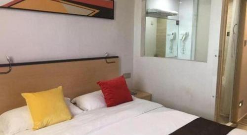 a bedroom with a bed with two colorful pillows at Cozy Hotel Xiamen in Xiamen